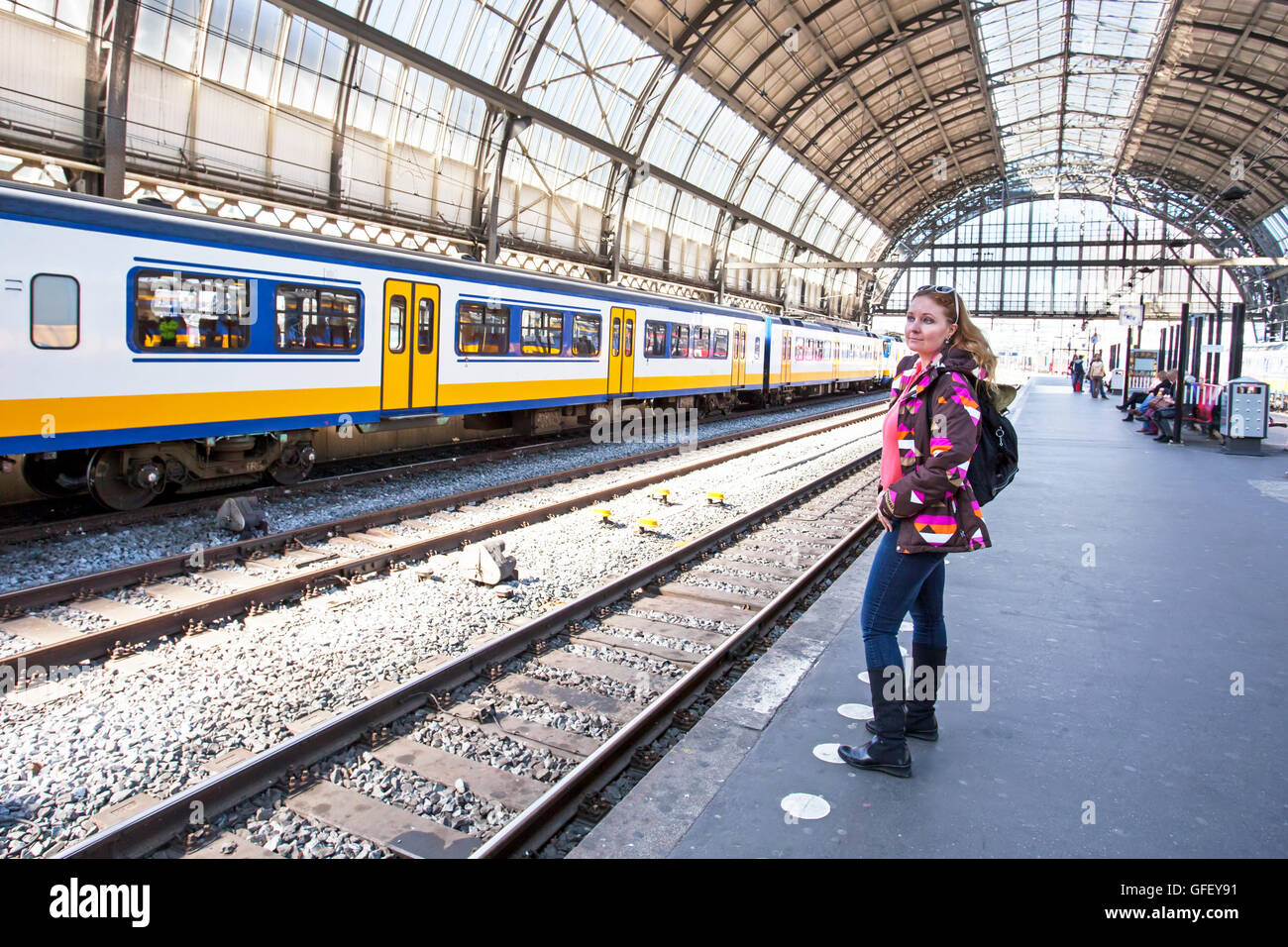 Giovane donna in attesa per il treno alla stazione centrale di Amsterdam Paesi Bassi Foto Stock