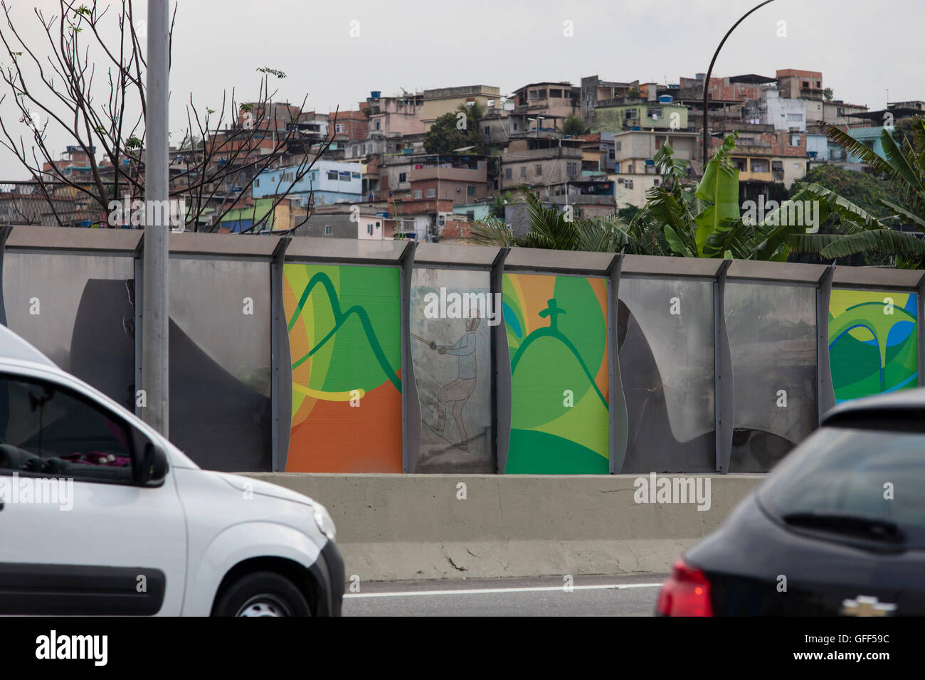 Complexo da mare, un enorme rete di favelas che affiancano la Linha Vermelha ( Linea Rossa ), la principale autostrada per l'aeroporto internazionale di Rio de Janeiro al centro della città - a partire dal 2010 la comunità è stata recintata dall'autostrada da enormi pannelli di Perspex - secondo le autorità forniscono una barriera acustica, la gente del posto lo descrivono come un "muro della vergogna", un altro modo di nascondere i poveri. Appena prima dei Giochi Olimpici la città cominciò intonacando i 3 metri di altezza, 7km del tratto di pannelli con colorati manifesti olimpici che mostra le principali della città paesaggi. Foto Stock