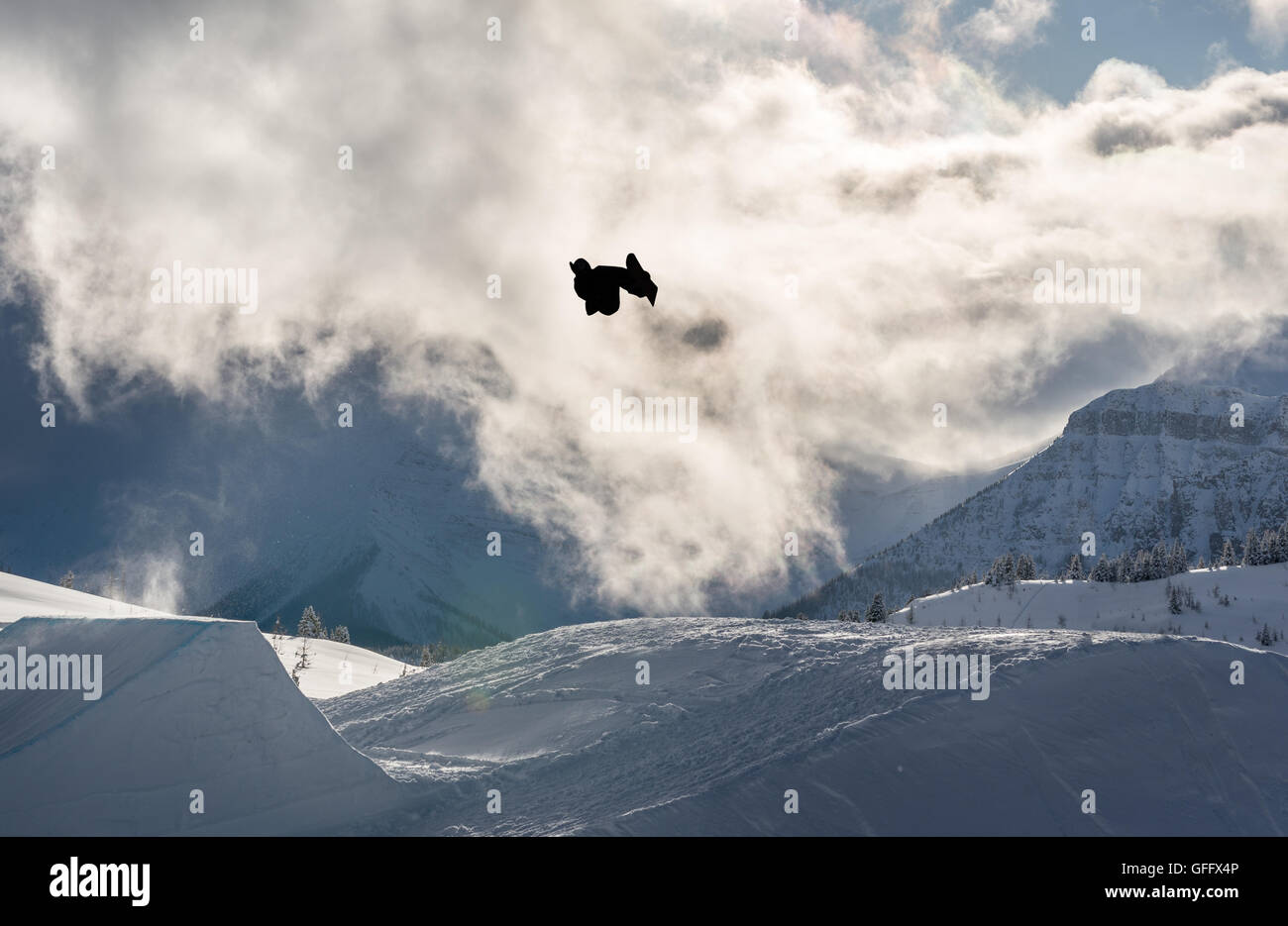 Snowboarder eseguendo un flip off un grande salto in montagna Foto Stock