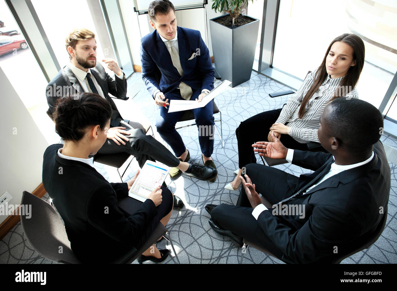 Il gruppo di cinque giovani discutendo di qualcosa mentre è seduto al tavolo in sede insieme Foto Stock