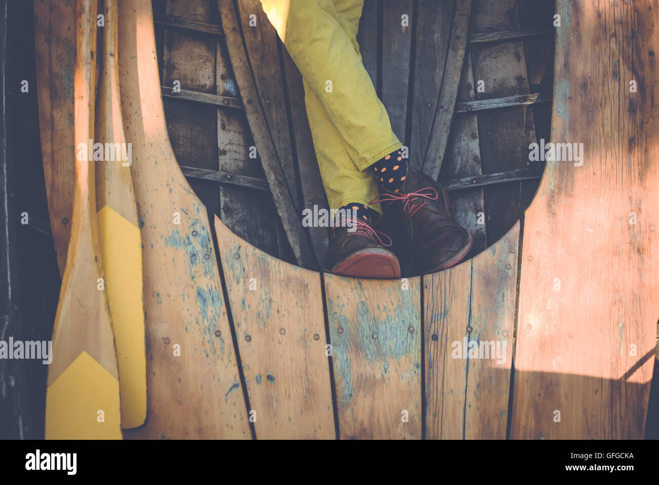 Uomo rilassato in colore giallo brillante pantaloni seduto in una barca a remi. Moda nautico. Foto Stock
