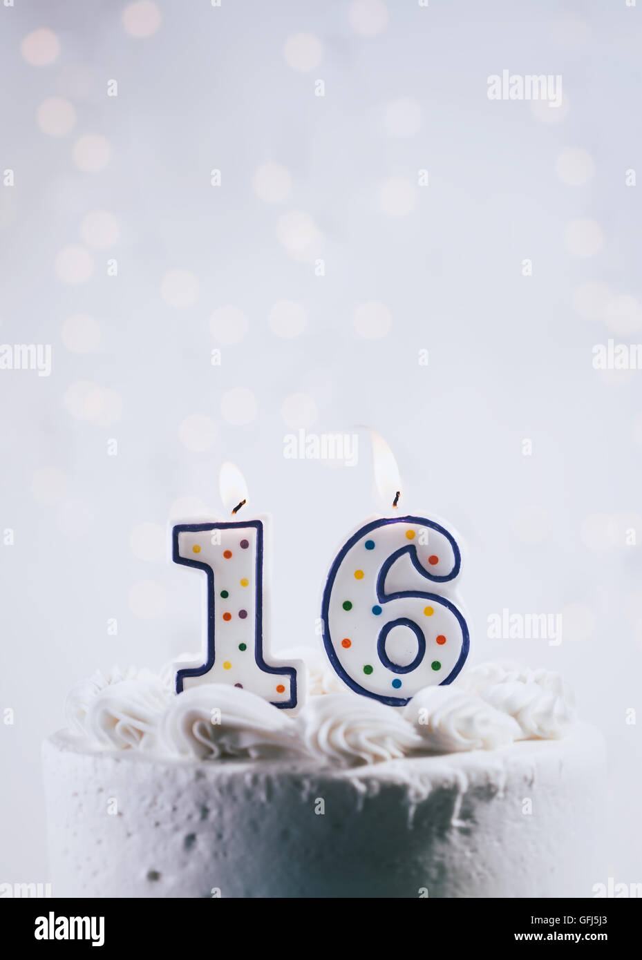 Bianco torta ghiacciata con candele e con luci incandescenti. Foto Stock