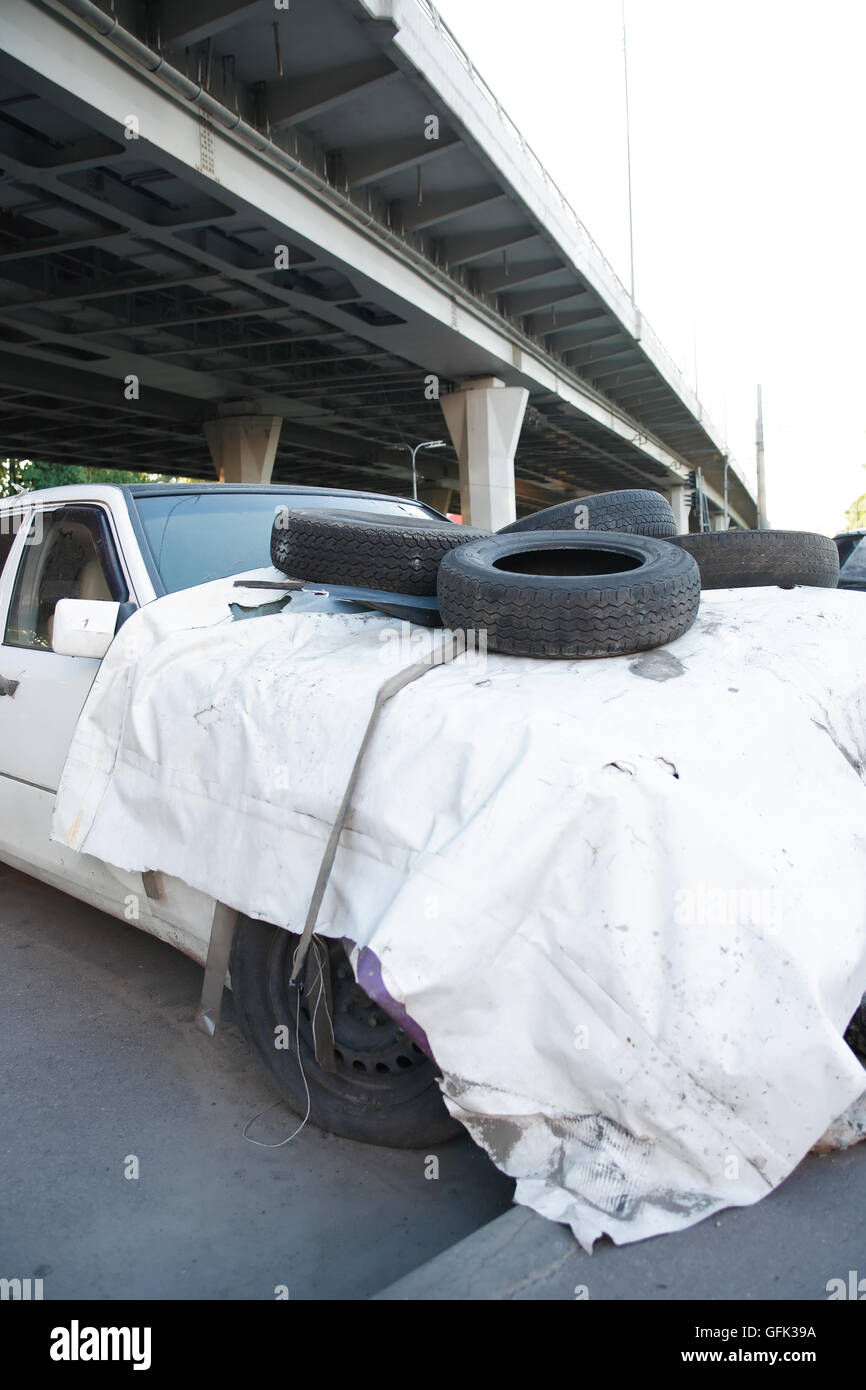 Vecchio e sporco auto abbandonate con pneumatici sotto il ponte in città Foto Stock