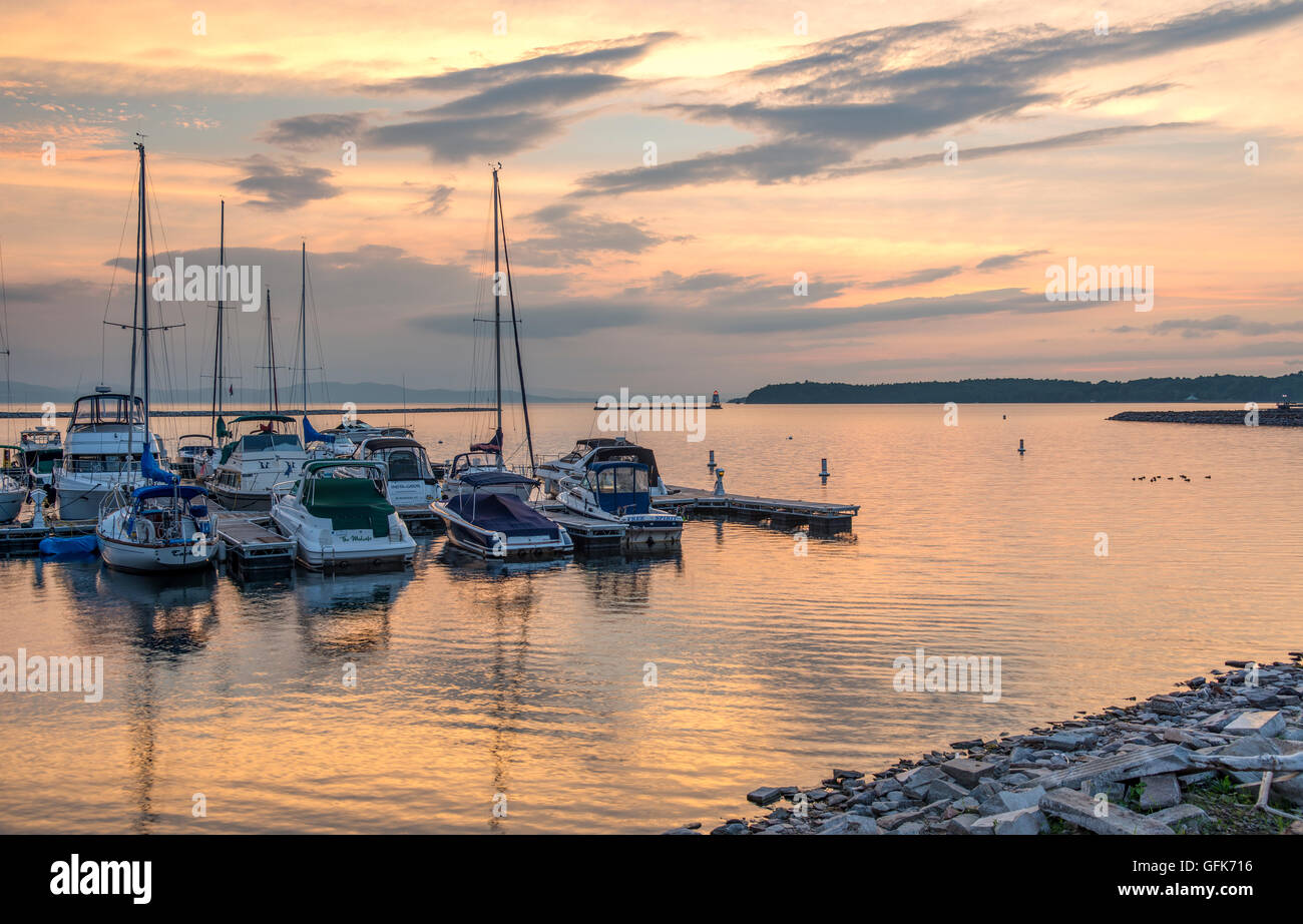 Scenografia colorata al tramonto delle barche ormeggiate sul lago Champlain, Burlington Vermont con vista del faro e delle montagne sullo sfondo. Foto Stock