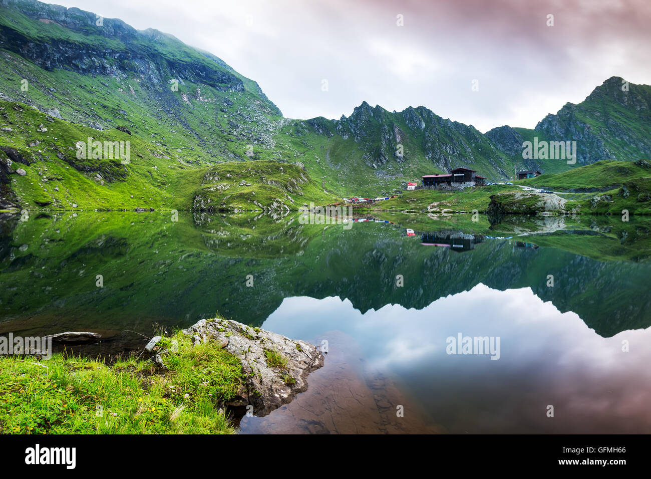 Specchio dei picchi di montagna nel lago glaciale con le nuvole e la nebbia nuvoloso Foto Stock