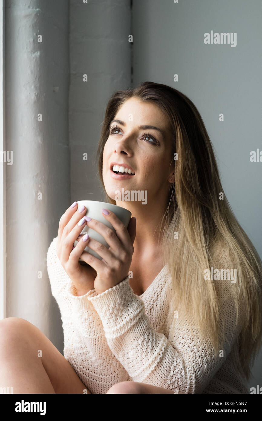 Sorridente attraente giovane donna con una bevanda calda Foto Stock