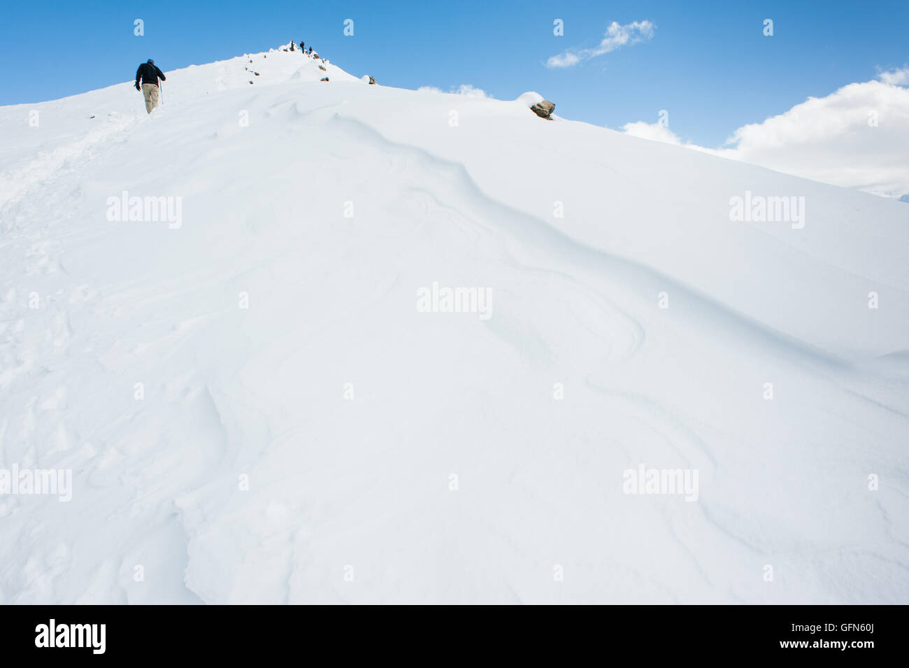 L'uomo escursionismo fino una coperta di neve montagna in Himalaya Foto Stock