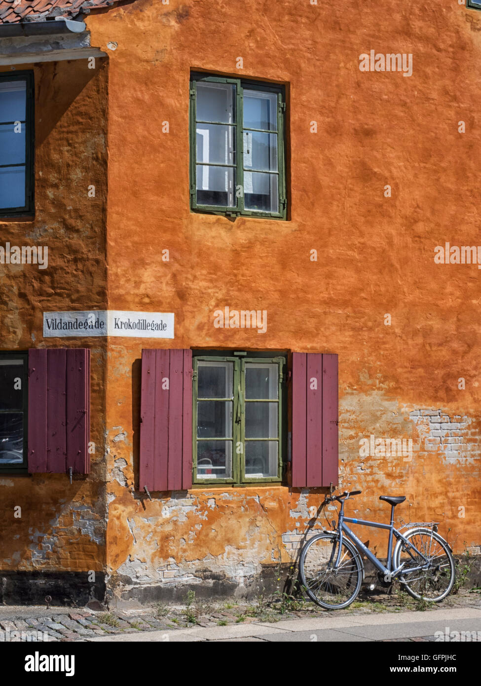 Angolo di una casa arancione in Nyboder con persiane marrone rossiccio e una bicicletta appoggiata contro il muro. Foto Stock