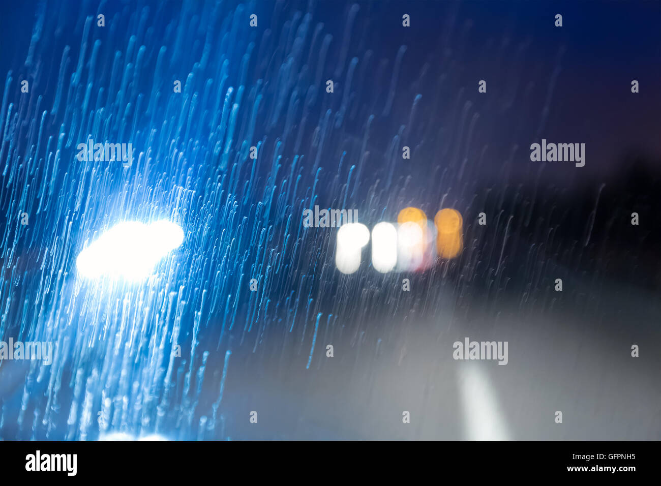 Strada in pioggia attraverso il parabrezza della vettura in movimento Foto Stock