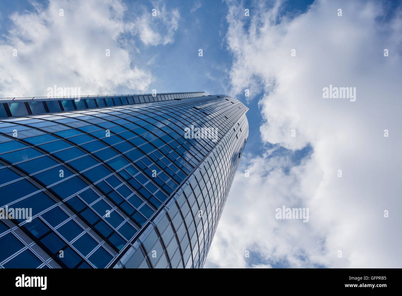 Guardando verso l'alto un edificio alto con un cielo nuvoloso sopra Foto Stock