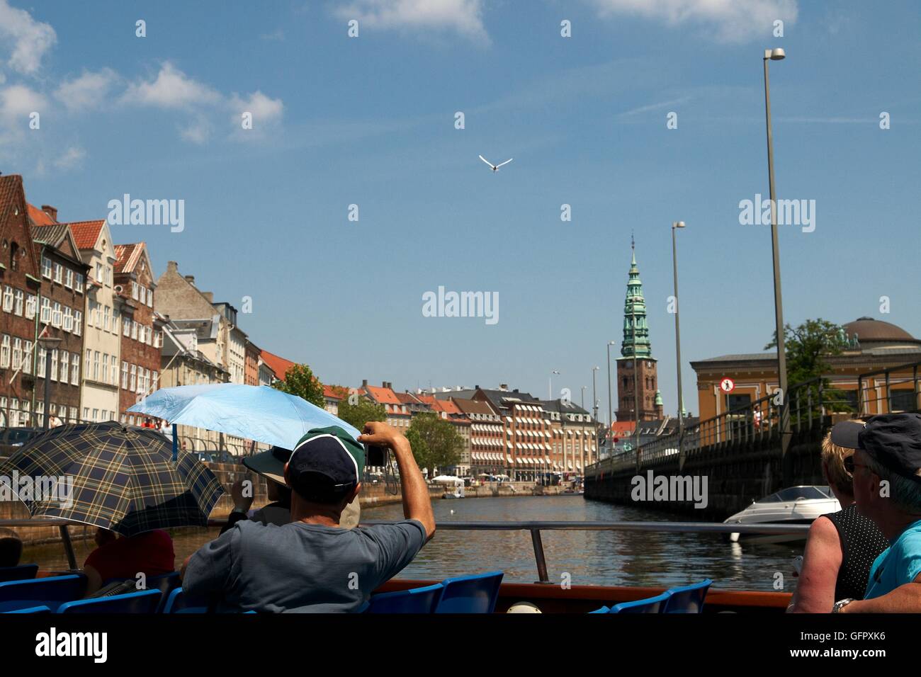 Turisti che si godono una gita in barca dei canali con Sct. Nikolajs chiesa in background - Copenhagen, Danimarca Foto Stock