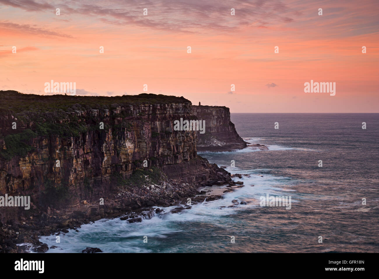 Pericoloso ruvida costa del nord capo a Sydney Harbour ingresso al tramonto rosa rivolta verso il sole e le nuvole. Foto Stock