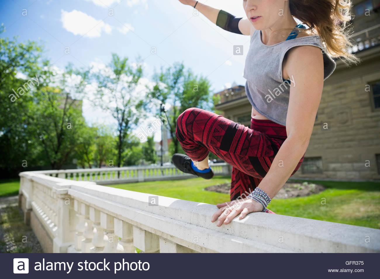 Giovane donna fare parkour saltando su parapetto Foto Stock
