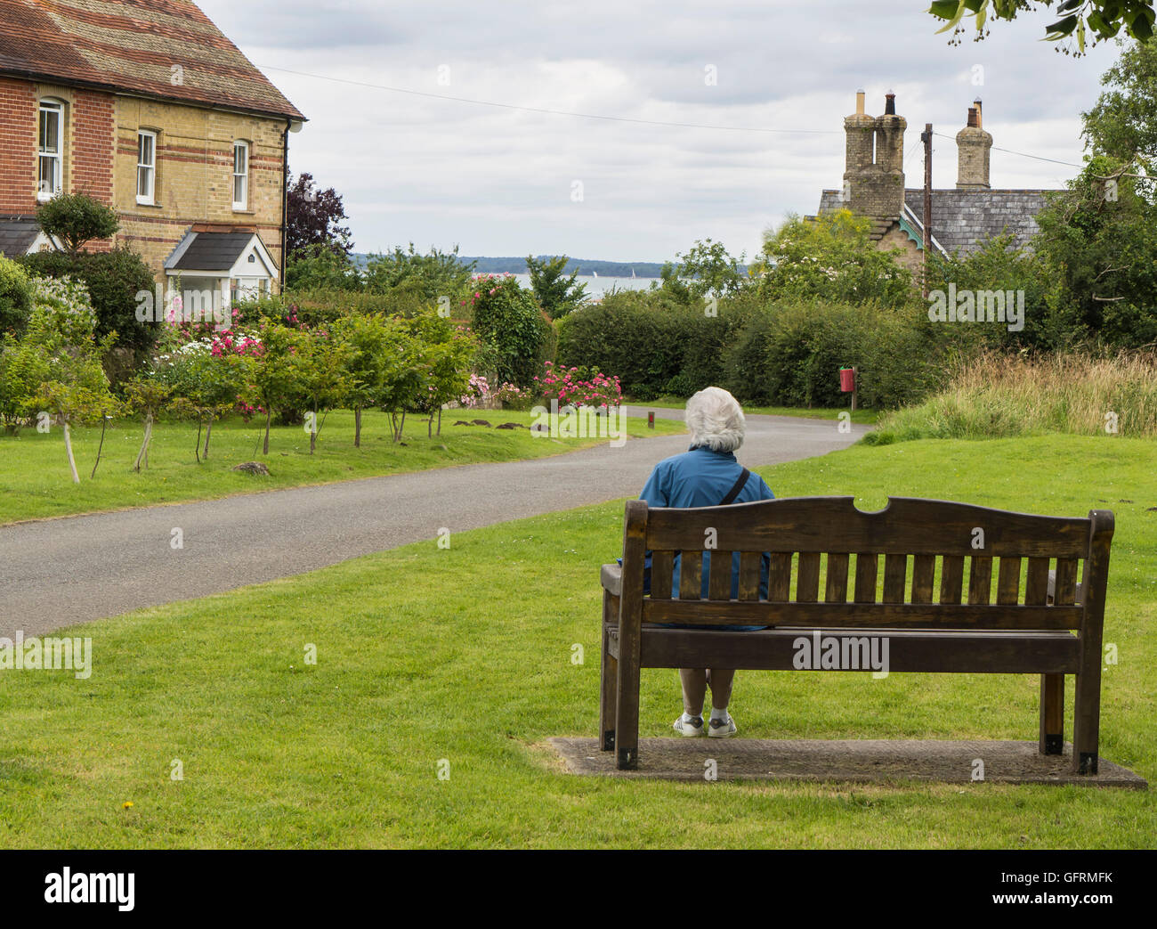 Una matura signora seduta da solo in un ambiente di villaggio sull'Isola di Wight, Regno Unito. Foto Stock