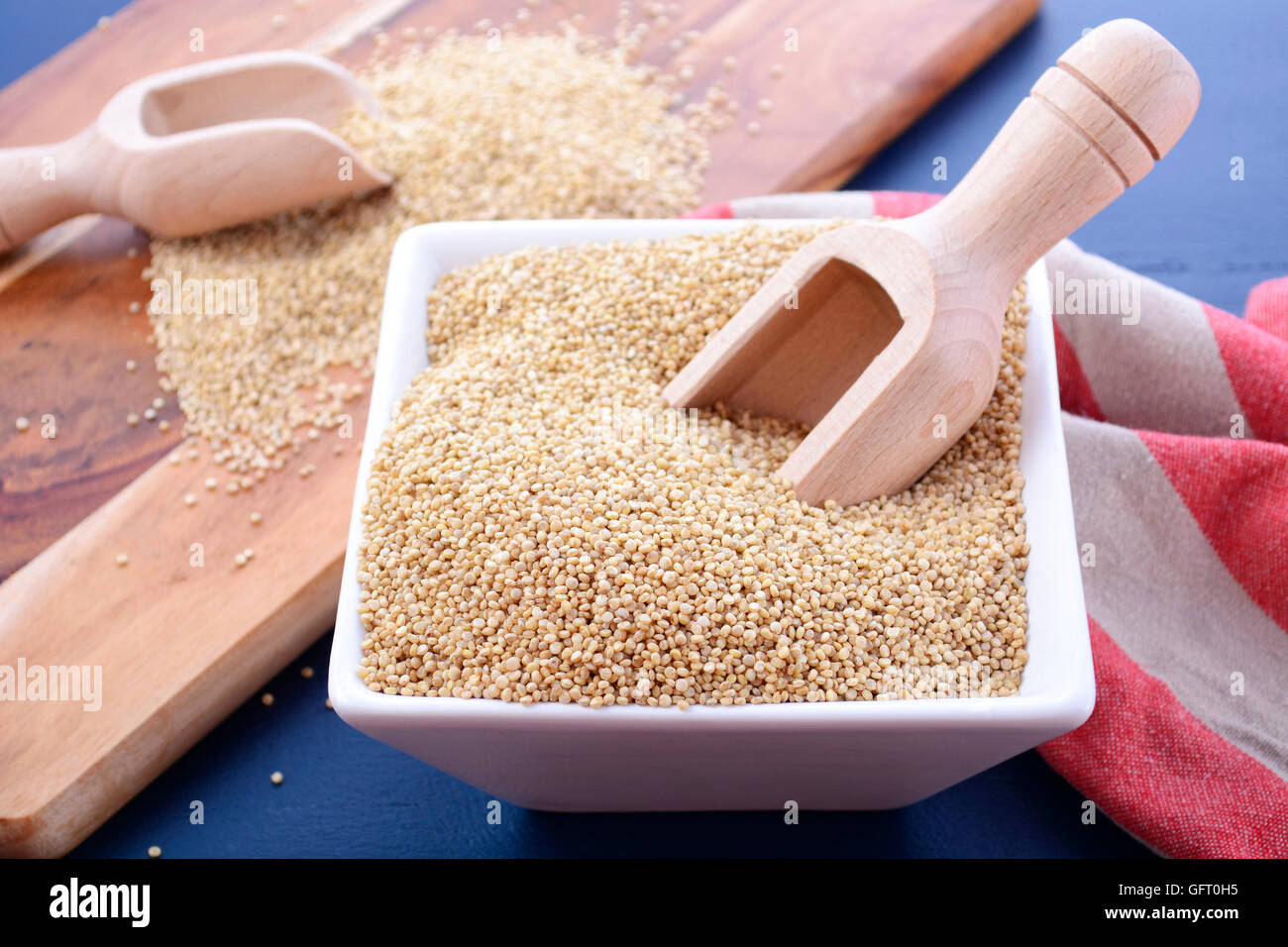 Grano bianco quinoa con palline di legno e tagliere in blu scuro dello sfondo di legno, primo piano. Foto Stock