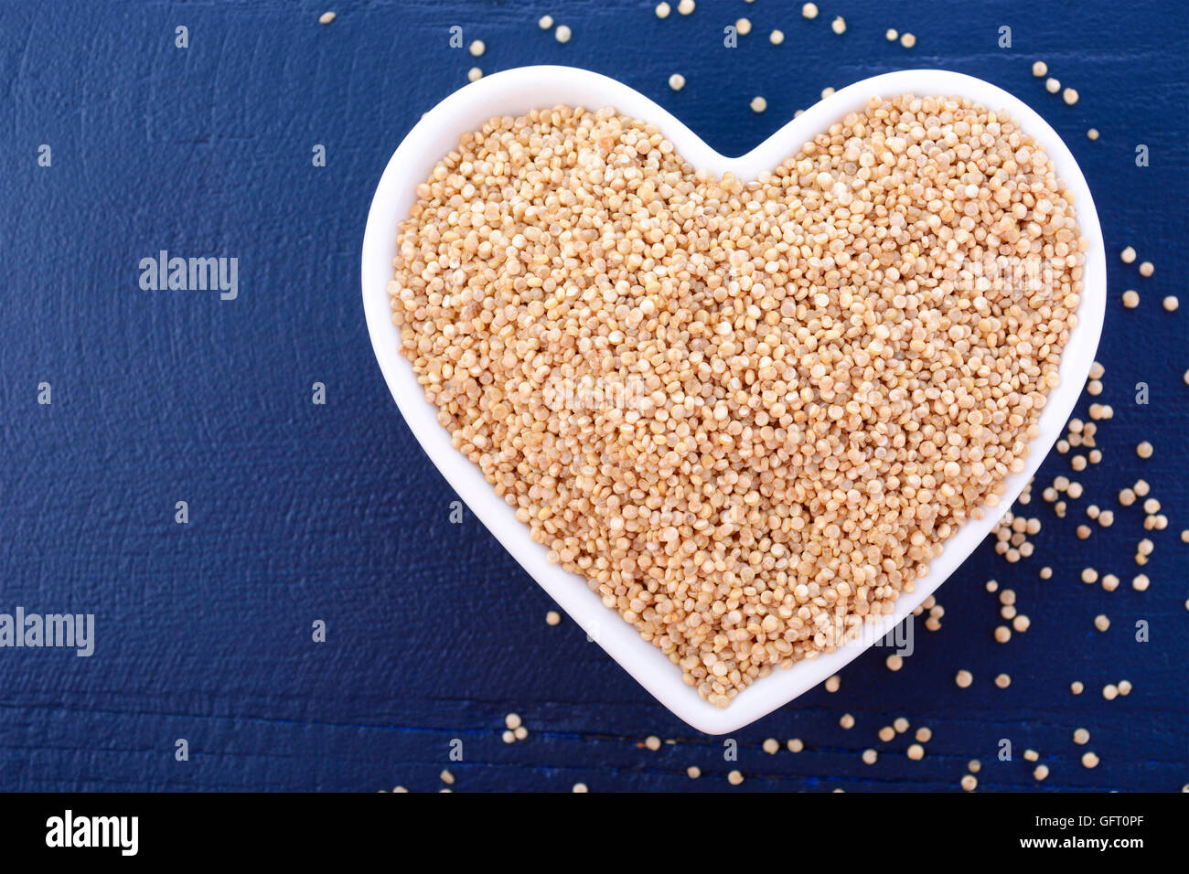 Io amo la quinoa concetto con grano bianco quinoa in bianco a forma di cuore sulla vaschetta un blu scuro Sfondo legno, primo piano con spazio di copia Foto Stock