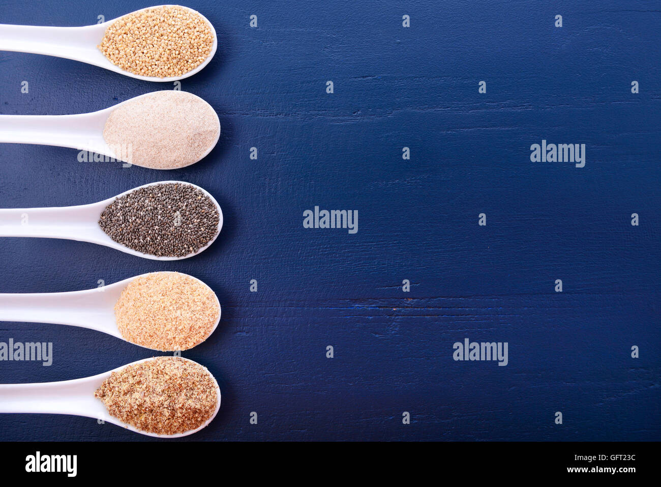 Granuli compresi, grano bianco quinoa, psillio lolla di polvere nera, Chia, il germe di grano e la massa LSA mix, sul blu scuro a grana di legno Foto Stock