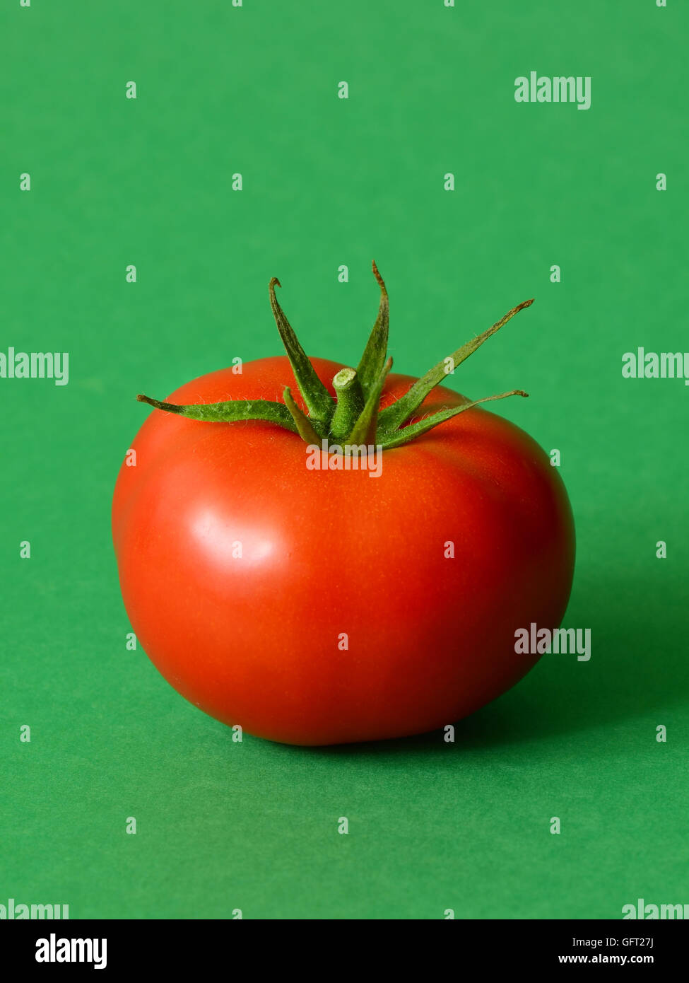 Un pomodoro maturo su uno sfondo verde Foto Stock
