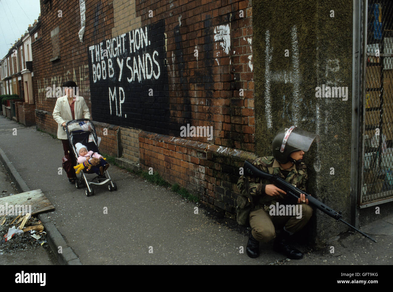 Guai Belfast degli anni ottanta Irlanda del Nord Regno Unito 1981 vita quotidiana la madre e il bambino armate soldato britannico di piede patrol Bobby Sands MP murale HOMER SYKES Foto Stock