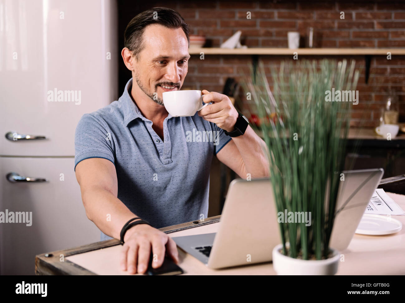 Uomo che guarda un notebook in cucina Foto Stock