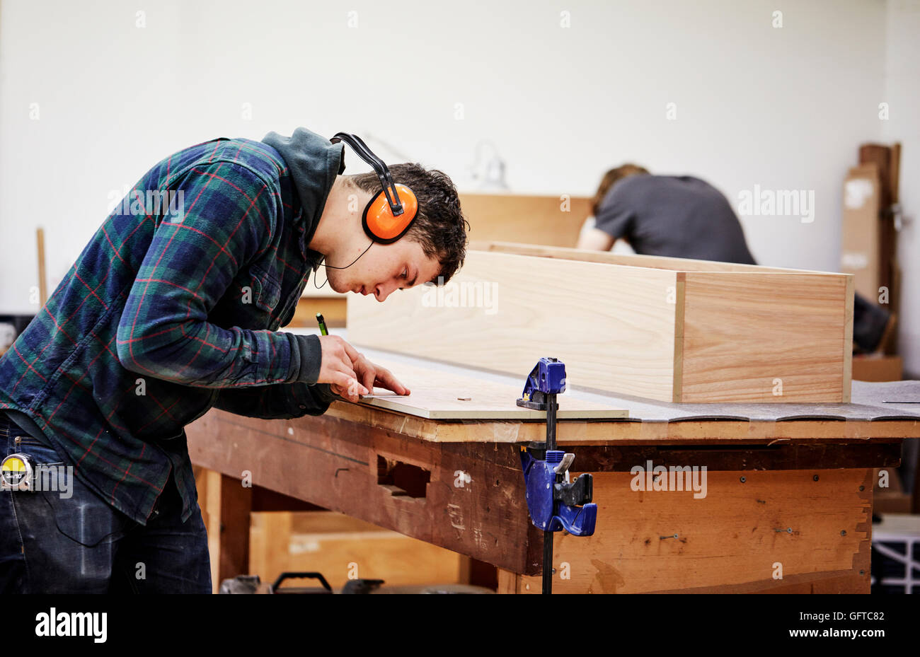 Un workshop di mobili un uomo segnando un pezzo di legno con una matita Foto Stock