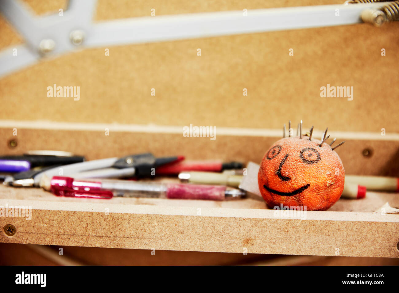 Un workshop di mobili mobili un banco di lavoro con la tecnica delle matite e dei pennarelli e essiccato arancio mandarino con un volto disegnato su Foto Stock