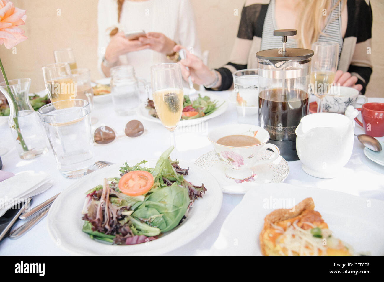 Angolo di alta vista di una tavola con cibi e bevande piastre con frittata e insalata caffè e champagne Foto Stock