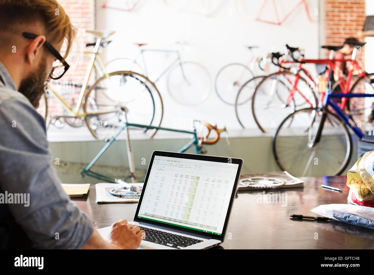 Un uomo in un negozio di riparazione di biciclette usando un computer portatile che esegue un business Foto Stock