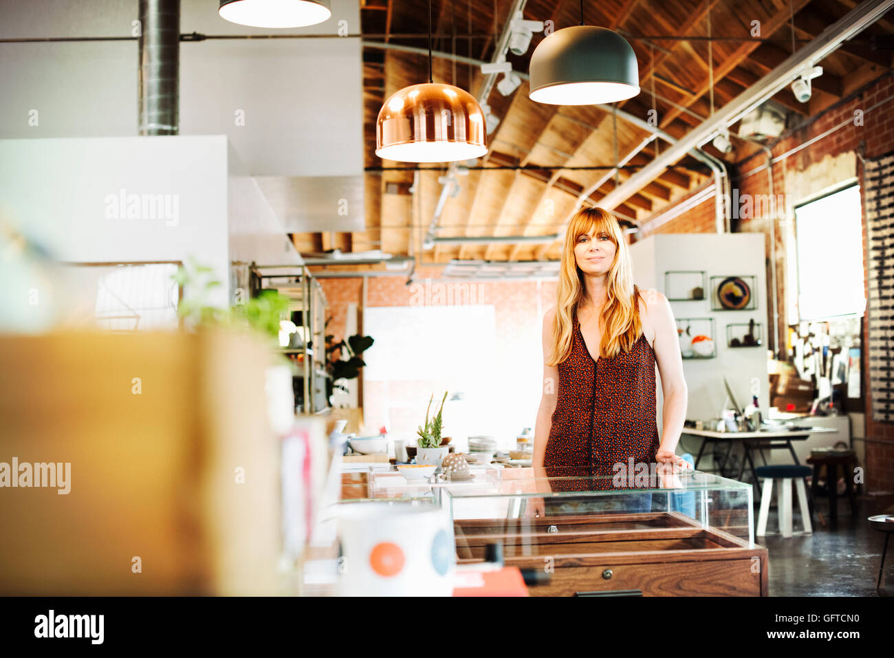 Donna con capelli lunghi biondi in piedi in un negozio di sorridere alla telecamera Foto Stock