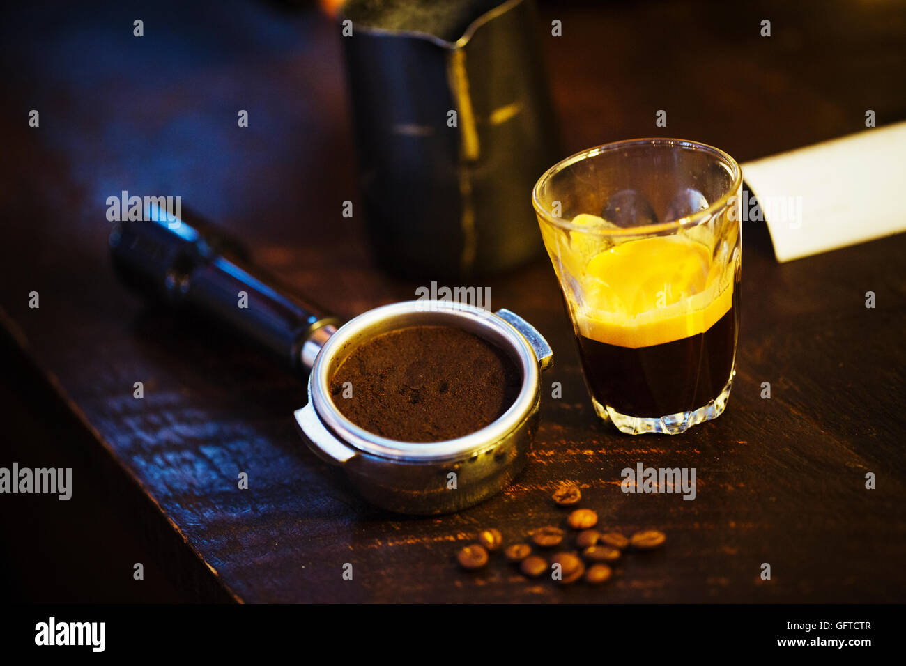 Una macchina da caffè motivi titolare un mucchio di chicchi di caffè e un bicchiere di vetro con caffè espresso Foto Stock