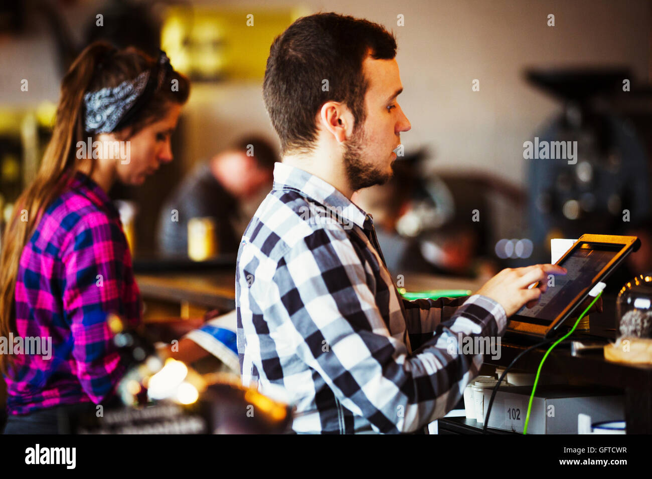 Una donna e uomo che lavora dietro il bancone da una macchina per la tostatura Foto Stock
