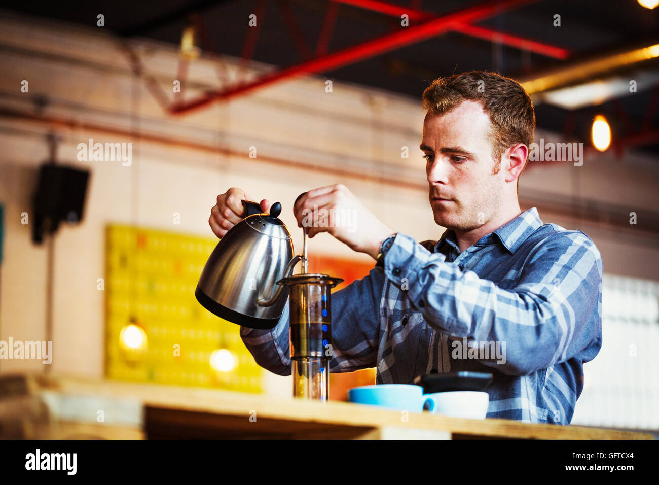 Un uomo versando acqua calda in una caffettiera Foto Stock