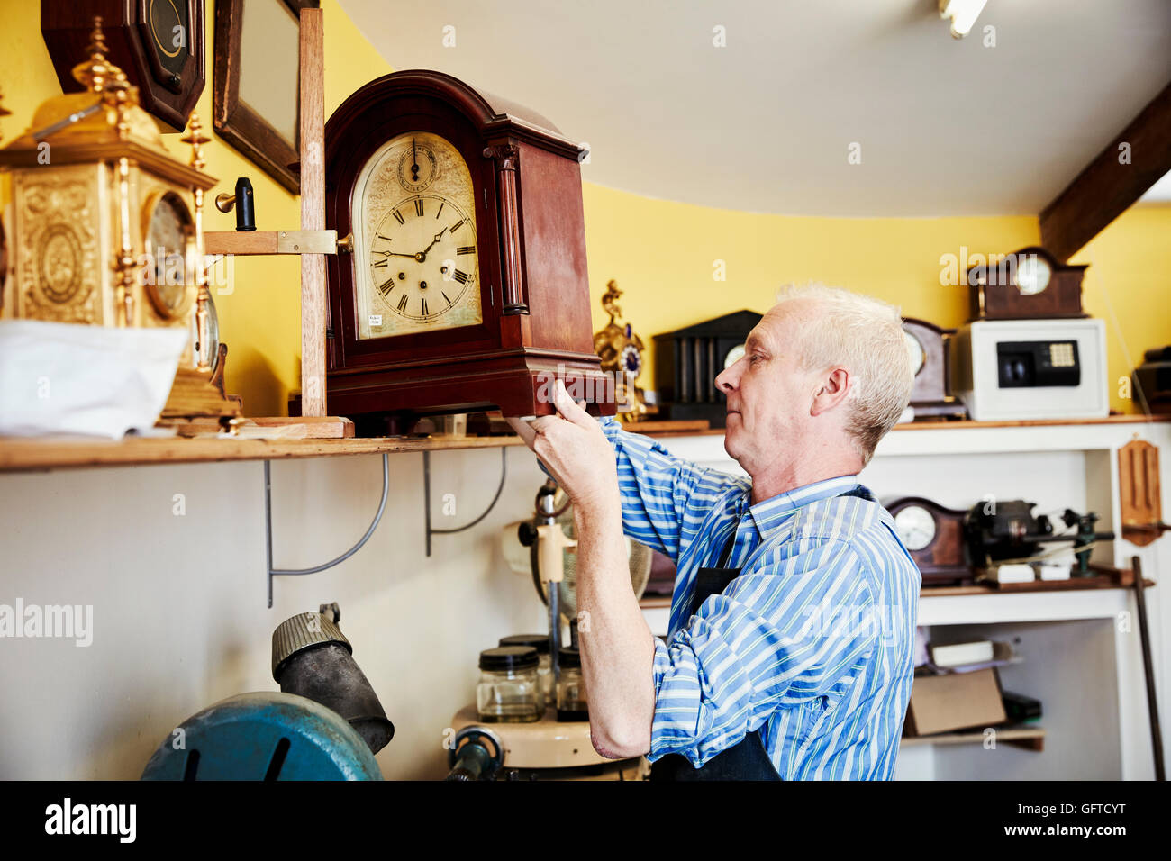 Un orologio maker visualizzando il suo lavoro su un ripiano nel suo laboratorio Foto Stock