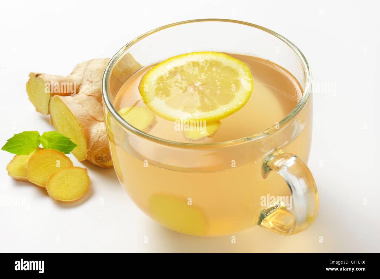 In prossimità della tazza di tè allo zenzero con limone e zenzero fresco su sfondo bianco Foto Stock