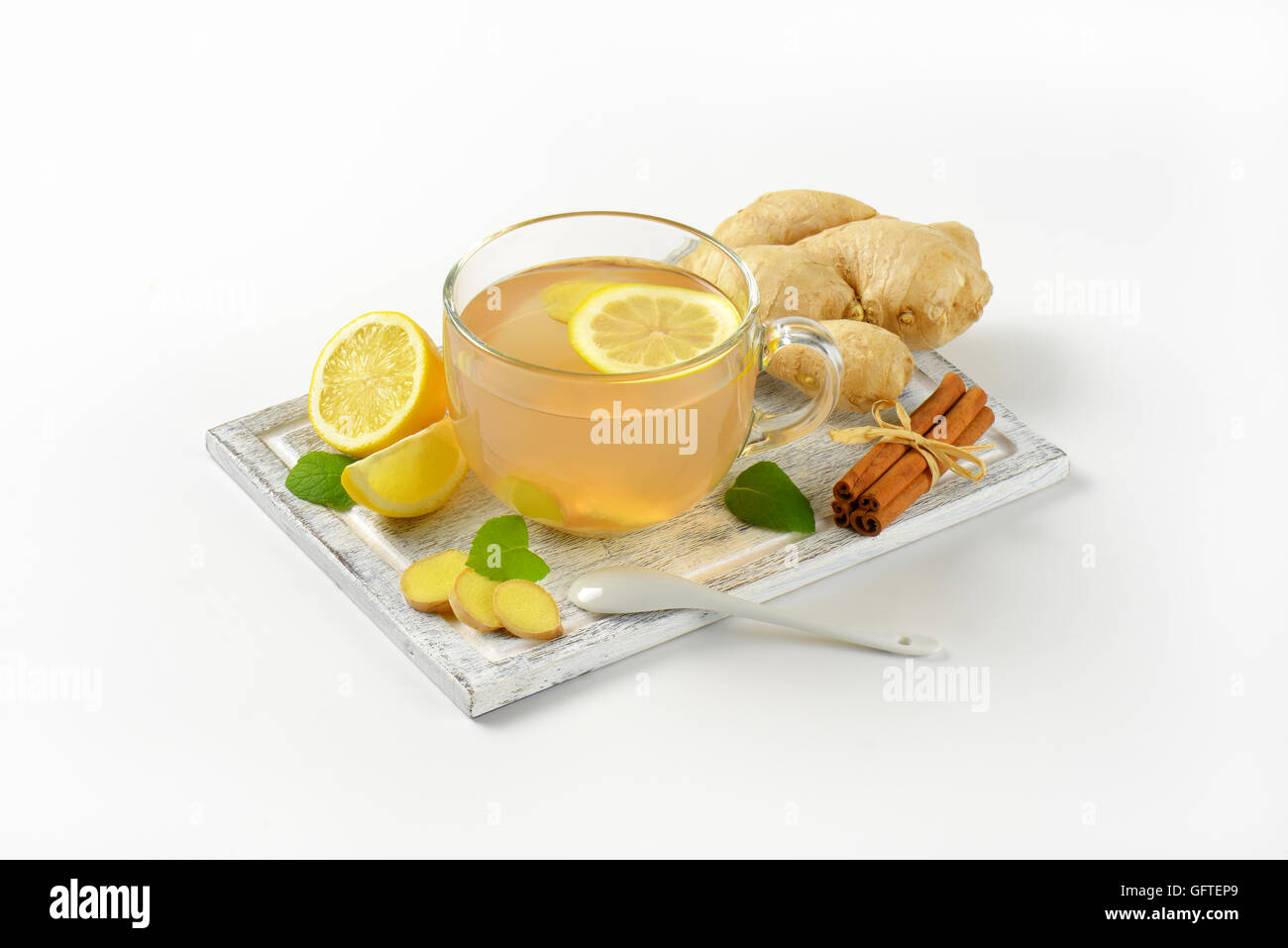 Tazza di tè allo zenzero con succo di limone, lo zenzero fresco e cannella sul tagliere di legno Foto Stock