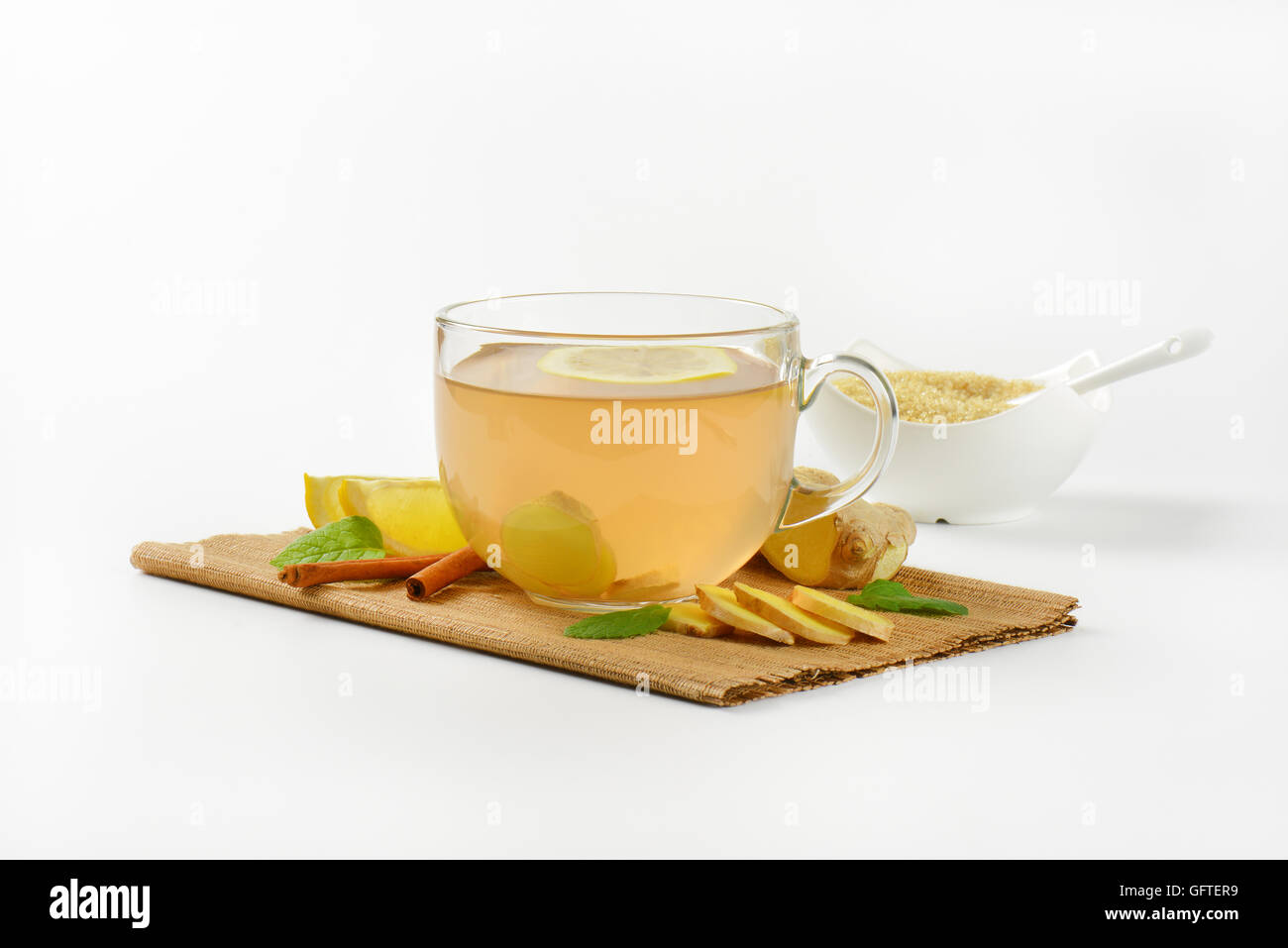 Tazza di tè allo zenzero con succo di limone, lo zenzero fresco e cannella sul tagliere di legno Foto Stock
