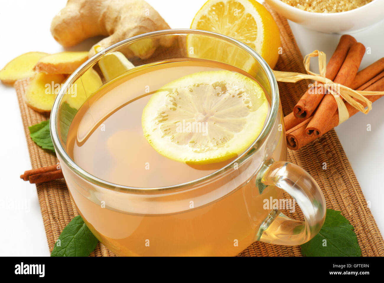 In prossimità della tazza di tè allo zenzero con succo di limone, lo zenzero fresco e cannella sul tagliere di legno Foto Stock