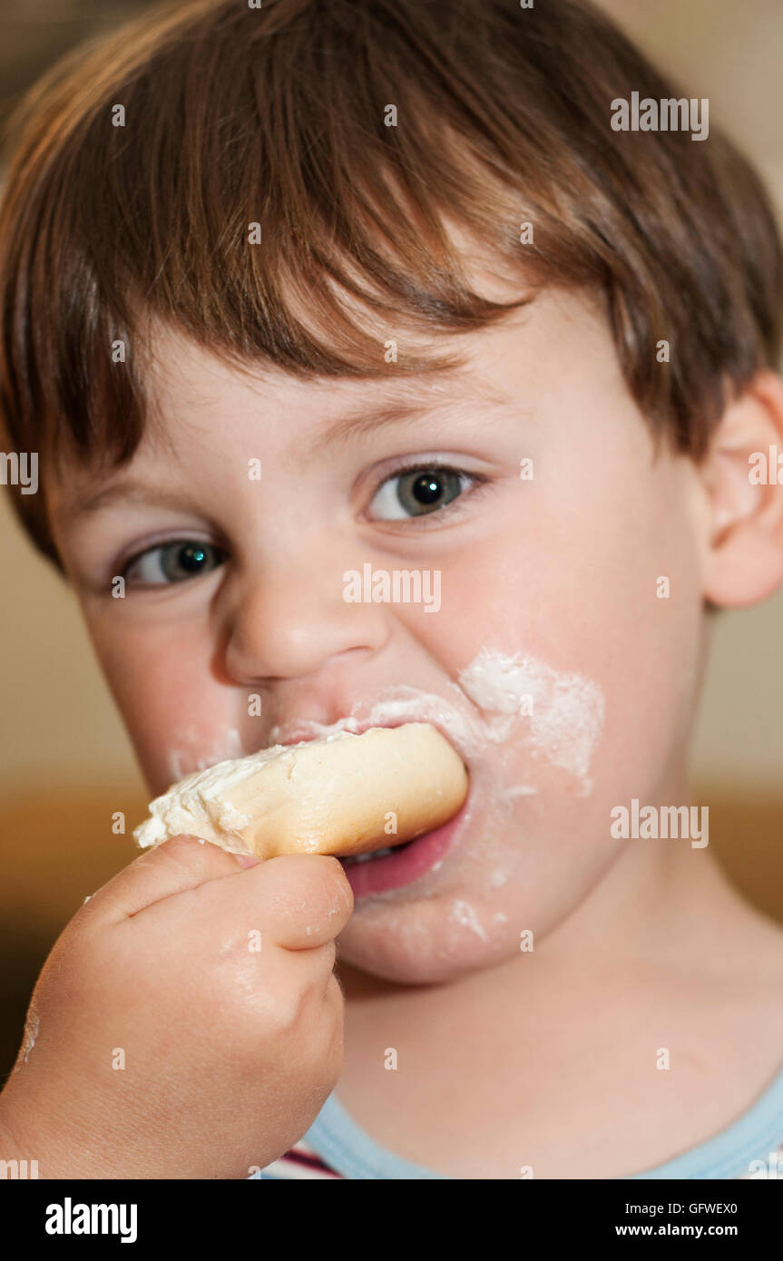 Un giovane bambino mangiare una ciambella. Foto Stock