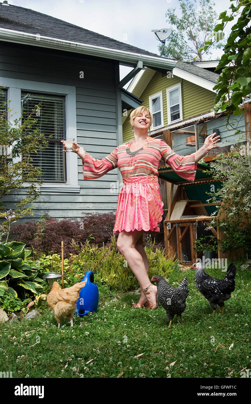 Un ritratto di una donna di Portland in piedi nel suo cortile interno con il suo piccolo gregge dei polli che utilizza per la deposizione delle uova. chic Foto Stock