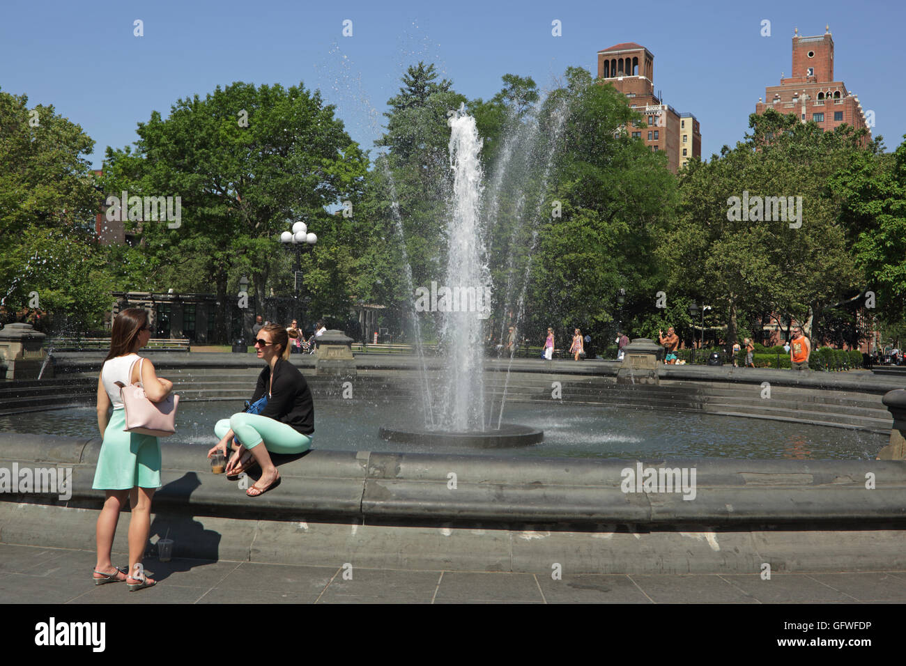 Due incognite giovani donne accanto alla fontana di Washington Square Park, New York, parlando Foto Stock