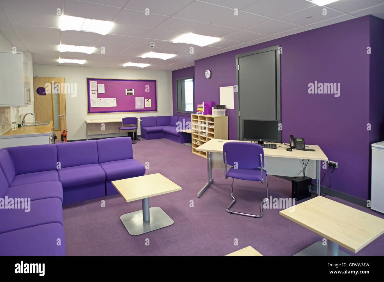Il personale di amministrazione e area ufficio in un nuovissimo Londra scuola primaria. Mostra scrivania e area di attesa. Schema di colore violaceo. Foto Stock