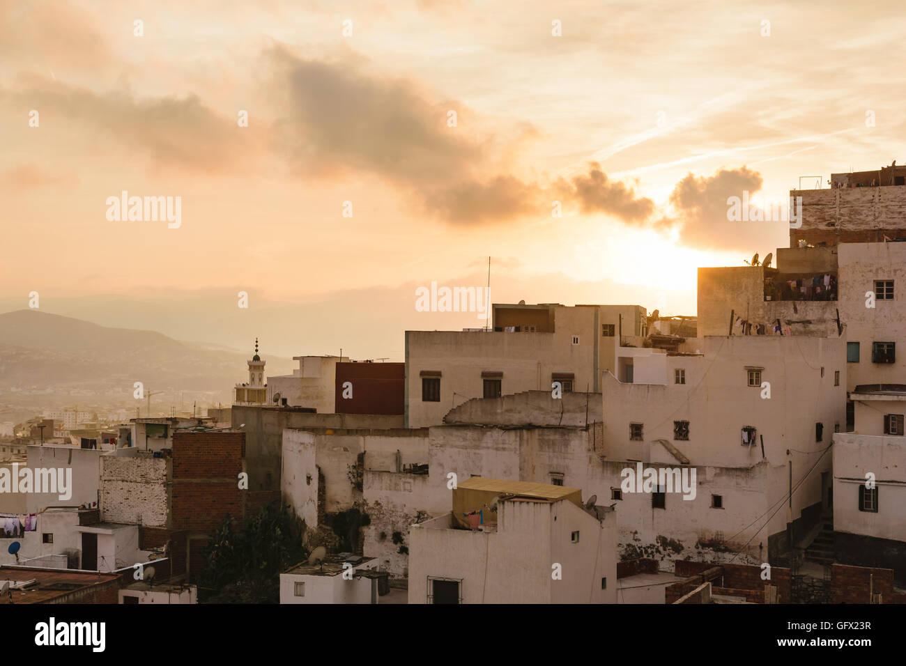 In prossimità di alcune vecchie case nella città di Tetouan in Marocco al tramonto. Il cielo è d'oro e vi sono poche nuvole nel cielo. Foto Stock