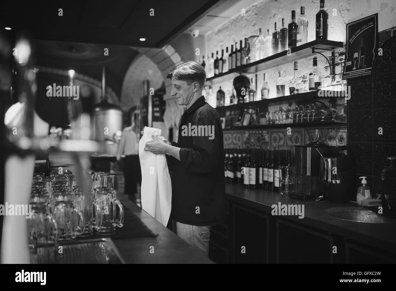Barman al lavoro nel pub sfrega contro il vetro Foto Stock