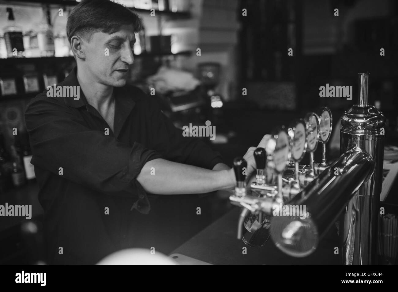 Barman al lavoro nel pub si versa la birra in un bicchiere Foto Stock