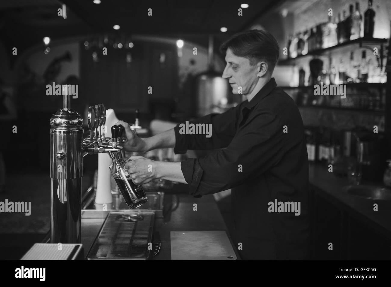 Barman al lavoro nel pub si versa la birra in un bicchiere Foto Stock