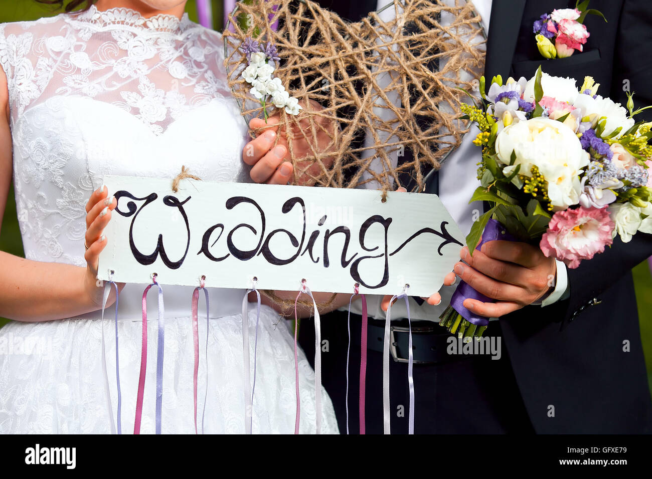 Decorazioni per matrimoni. Targa di legno con la scritta di un matrimonio. Wedding su una piastra di sfondo verde e una fontana. Decorazioni per matrimoni. Foto Stock