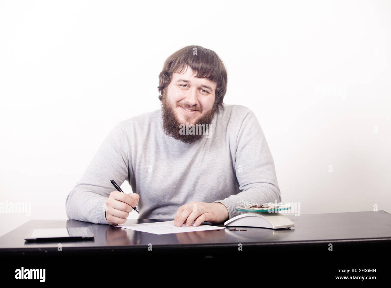 Giovane uomo d affari firma un contratto seduto alla scrivania in ufficio Foto Stock