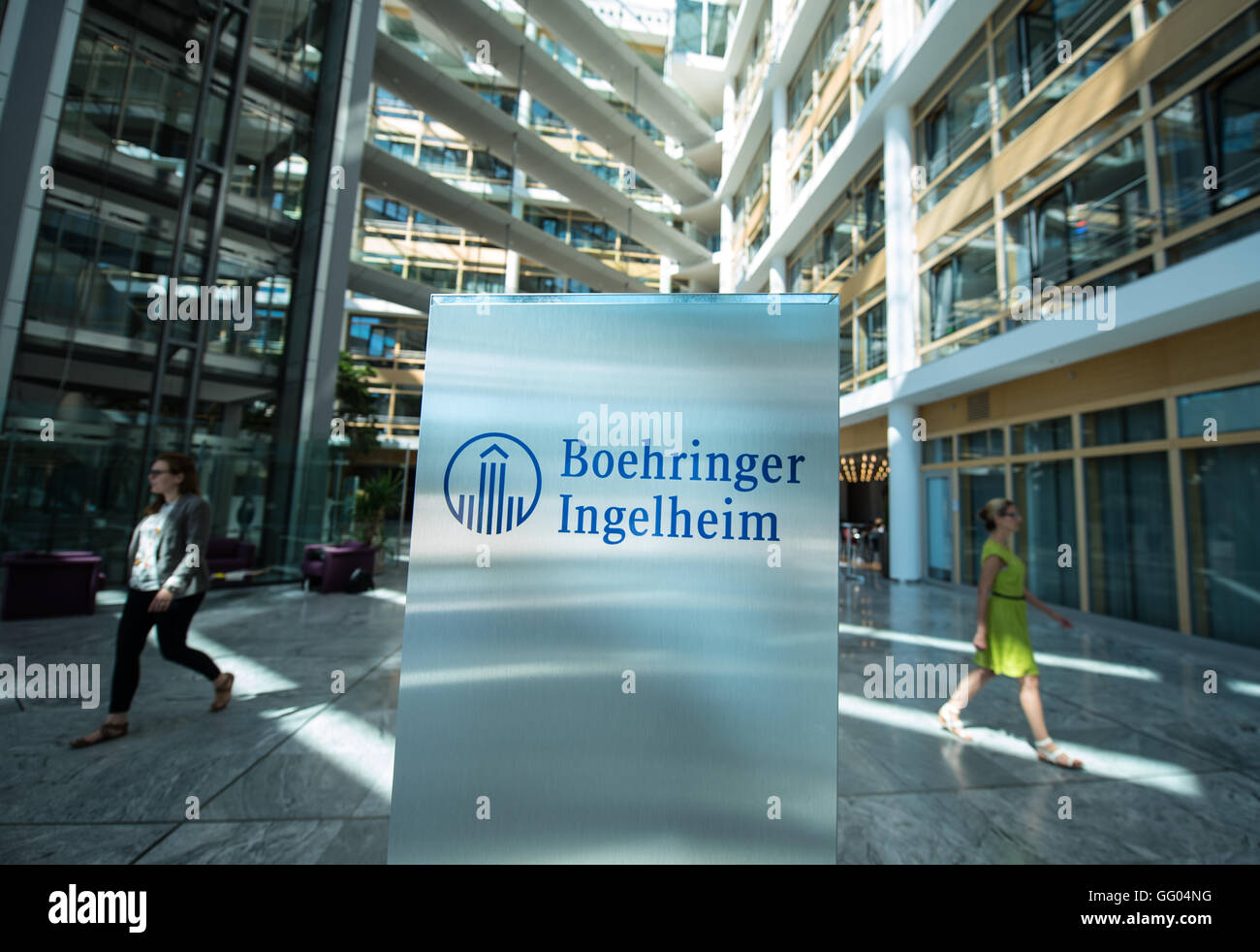 Due dipendenti a piedi passato il logo aziendale della società farmaceutica Boehringer Ingelheim presso la sede centrale della società in Ingelheim am Rhein, Germania, 23 giugno 2016. Foto: Andreas Arnold/dpa Foto Stock