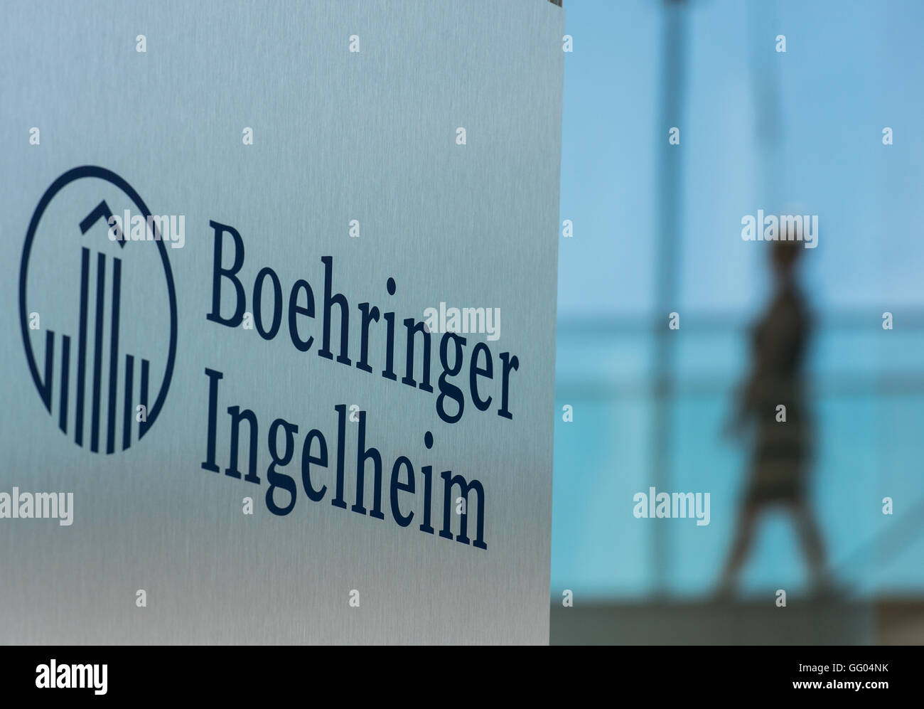 Il logo aziendale della società farmaceutica Boehringer Ingelheim può essere visto nella parte anteriore di un ponte di vetro che un dipendente è a piedi attraverso in Ingelheim am Rhein, Germania, 23 giugno 2016. Foto: Andreas Arnold/dpa Foto Stock