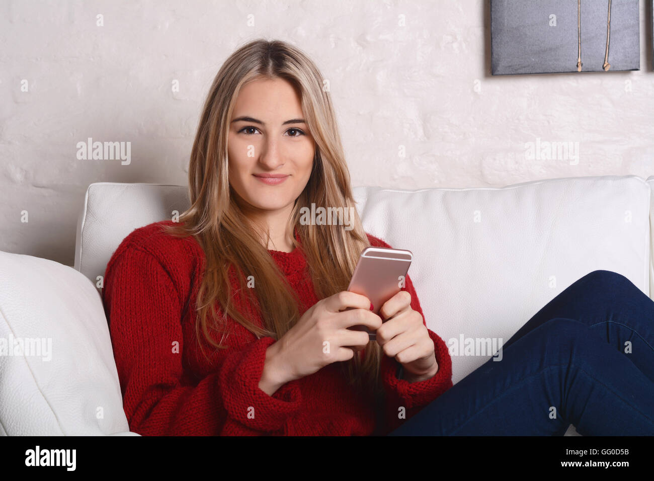Ritratto di una giovane e bella donna l'invio di messaggi con lo smartphone. In ambienti chiusi. Foto Stock